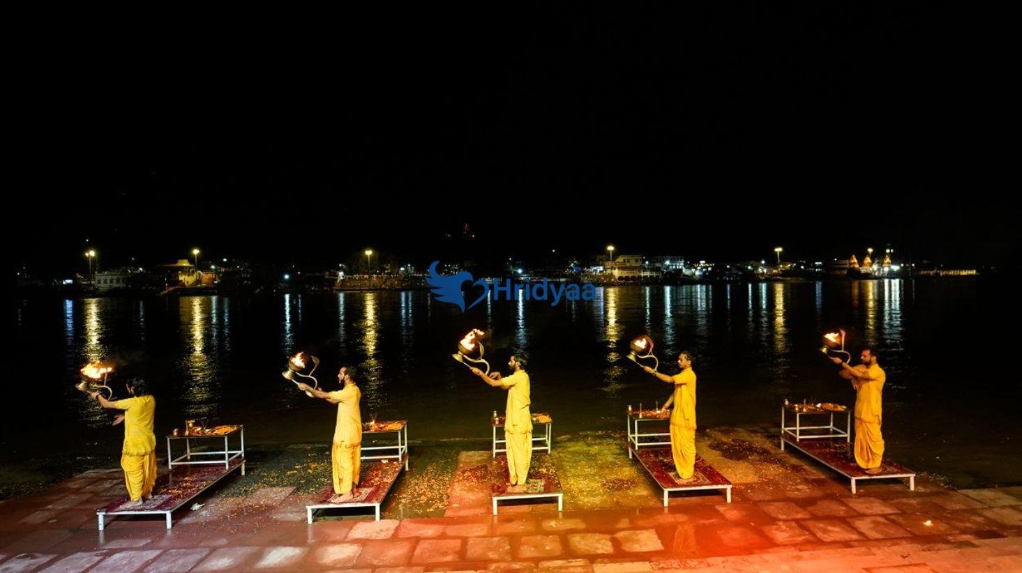 Triveni Ghat in Rishikesh during the evening Ganga Aarti with lamps and devotees along the riverbank